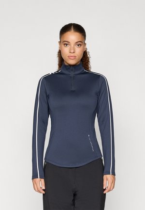 Tengerészkék, hosszú ujjú zipzáras felső, magas gallérral, fehér oldalsávokkal és sima, rugalmas anyagból készült. Logó részlettel díszítve.