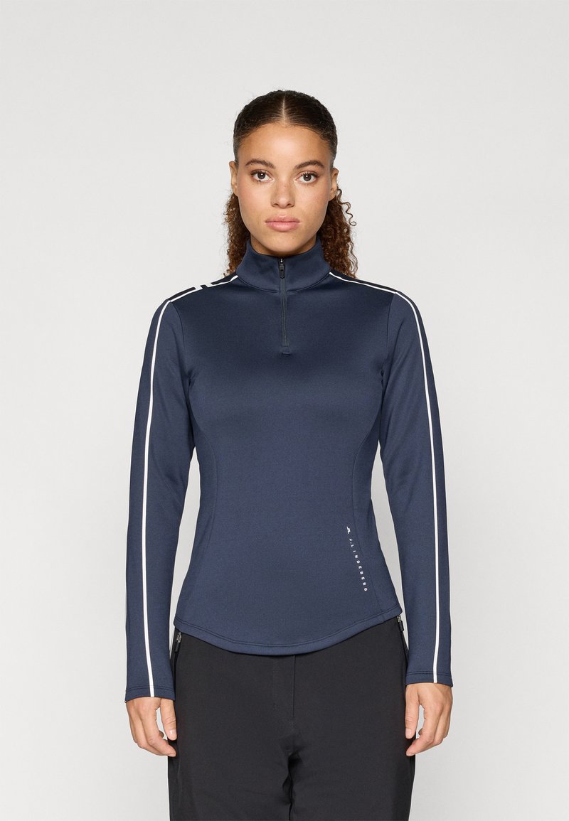 Námořnická modrá mikina na zip s dlouhým rukávem a vysokým límcem, s bílými bočními pruhy a hladkým, elastickým materiálem. Ozdobena logem.