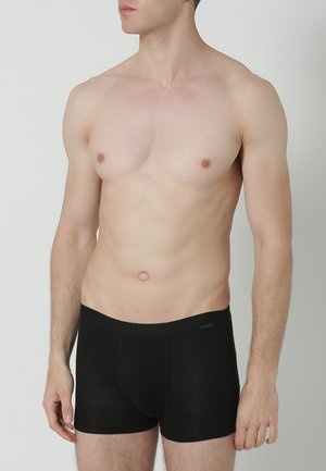 Boxer-culottes noires en tissu doux, offrant un ajustement confortable et une ceinture élastique. Le design est simple, sans motifs ni accents visibles.