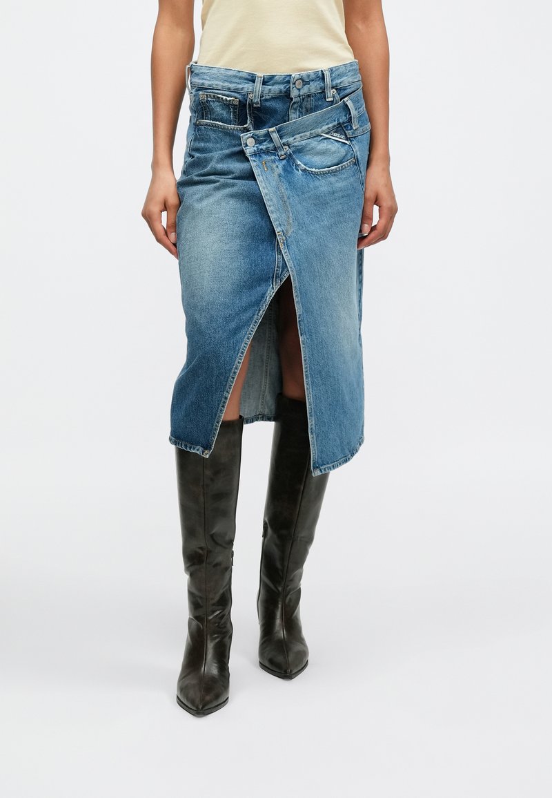 Η τζιν φούστα διαθέτει μοναδικό σχέδιο τύλιξης, ανοιχτό μπλε χρώμα, μεσαίο μήκος με άνοιγμα στο μπροστινό μέρος και αντίθετες τζιν τσέπες.