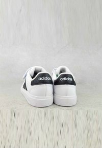 Sneakers bianche con tappi del tallone neri, caratterizzati da una tomaia sintetica liscia, punta tonda e design a tre strisce in contrasto.