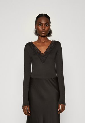 Crni bodysuit dugih rukava s dubokim V-izrezom i čipkastim obrubom. Mekani, glatki materijal s uskim dizajnom i elegantnom siluetom.