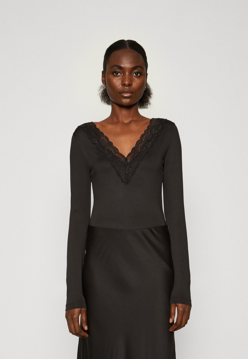Must have pikkade varrukatega must bodysuit, millel on sügav V-kujuline kaelus koos pitsäärisega. Pehme ja sile materjal, mis on vormitud disaini ja elegantse siluettiga.