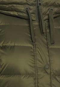 Olivgrüne Steppjacke mit gesteppten Einsätzen, Reißverschluss vorne, Kordelzugkapuze und einem runden schwarzen Knopfakzent.