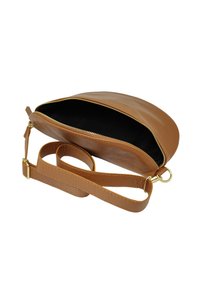 Sac en cuir tan à bandoulière avec une forme arrondie, fermeture zippée et intérieur noir. Il dispose d'une bandoulière détachable et de quincaillerie dorée.