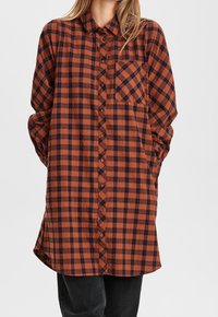 Camicia in flanella a quadri arancione e blu navy, con una chiusura a bottoni sul davanti, colletto, tasca sul petto e vestibilità rilassata con maniche lunghe.