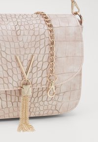 Borsa a tracolla in ecopelle rosa con texture a coccodrillo, accenti in metallo dorato, chiusura a fibbia a forma di V, tracolla a catena e dettaglio con nappina.