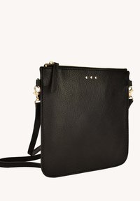 Sac en cuir noir à bandoulière avec trois clous décoratifs en métal, fermeture zippée et sangle réglable. Texture lisse et bords nets.