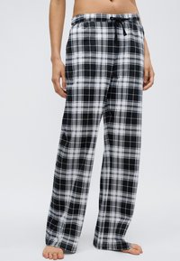Svartvita flanellbyxor med rutigt mönster, lös passform, elastisk midja och dragsko. Tillverkade av mjukt tyg med rutigt mönster.