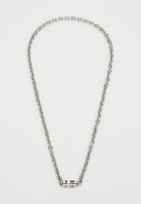 Silberne Gliederkette mit einem kleinen zylindrischen Anhänger, der rot-, weiß- und blaufarbene Streifen sowie dezente Markeninschrift aufweist.