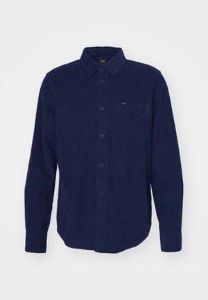Granatowa koszula z korduroyu z długim rękawem, z kołnierzykiem zapinanym na guziki, kieszenią z przodu oraz subtelnym detalem teksturalnym. Posiada oznaczenie marki przy kołnierzyku.