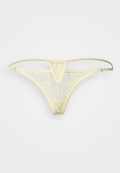 Κίτρινο δαντελένιο στρινγκ με τριγωνικό εμπρόσθιο σχέδιο, ελαστικά λουριά και κυματιστά άκρα. Το υλικό έχει λουλουδάτο μοτίβο με διαφανείς περιοχές.