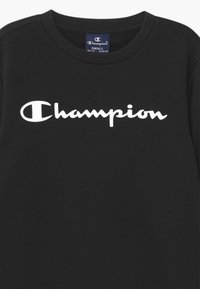 Sweatshirt nero piccolo del marchio Champion con testo logo bianco sul petto e un'etichetta blu con la taglia all'interno del colletto.