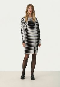 Abito a righe in crema e navy con maniche lunghe, scollatura rotonda e una vestibilità morbida che arriva sopra il ginocchio.