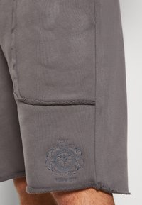 Grijze katoenen shorts met een textuurafwerking, voorzien van rafelige randen en een blauw geborduurd logo aan de zoom.