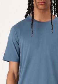 Short-sleeve blue cotton t-shirt with a crew neckline, smooth texture, and minimal stitching details, showing a relaxed fit.