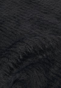 Tissu noir texturé avec une surface épaisse et duveteuse, présentant des nuances variées de noir et de gris profond, créant un aspect stratifié.