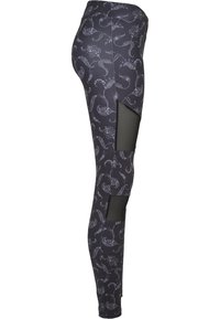 Musta leggings, joissa on valkoinen kukkakuosi ja verkkoleikkaukset sivuilla. Valmistettu joustavasta ja hengittävästä materiaalista. Slim fit -muidot.