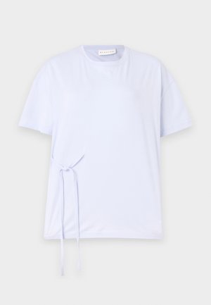 Camiseta de algodón azul claro con manga corta, cuello redondo y un detalle de lazo en el lateral. Textura suave y ajuste casual.