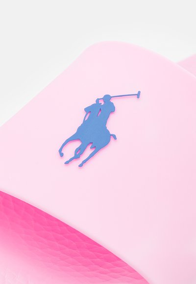 Chinelo de borracha rosa com um superior texturizado e um logótipo de jogador de polo azul na tira. Acabamento suave com uma forma arredondada.