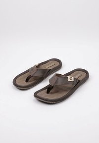 Chanclas marrones con una correa de tela texturizada, plantilla suave y suela de goma. Incluye un pequeño logo circular en la correa.