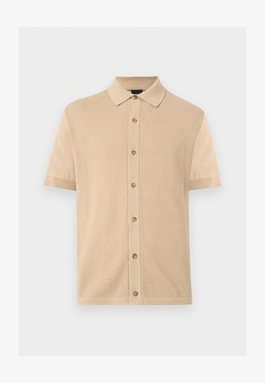 Polo beige à manches courtes avec panneau avant texturé, fermeture boutonnée et manches lisses sur un fond clair uni.