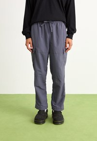 Graue Cargo-Hosen aus leichtem Material, mit einem elastischen Bund, zwei Seitentaschen und einer lockeren Passform.