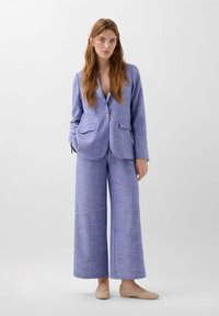 Blauwe linnenmix blazer met twee voorzakken, sluiting met één knoop, gecombineerd met bijpassende wijde broek, gestructureerde stof en platte schoenen.