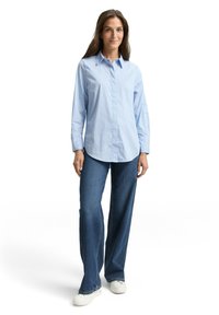 Blue and white striped long-sleeve shirt with a collared neckline, paired with wide-leg dark denim jeans and white sneakers.