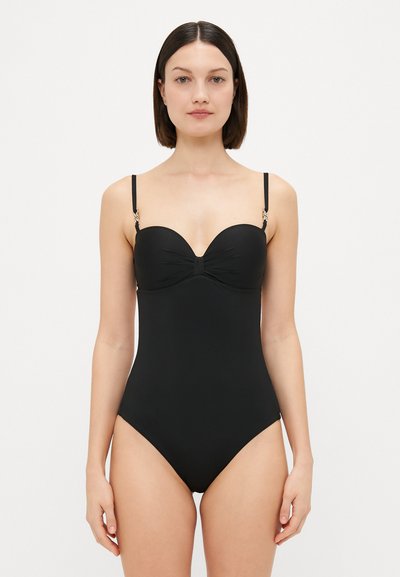 Zwarte badpak met een sweetheart halslijn, zachte rimpeldetails, verstelbare banden en gouden hardware accenten. Glad textuur van de stof.