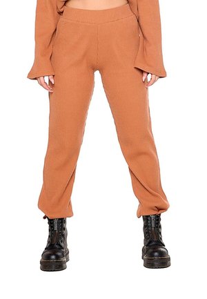 Modèle portant un pantalon côtelé rouille à jambes larges et des bottines noires à lacets et à plateforme, sur fond blanc.