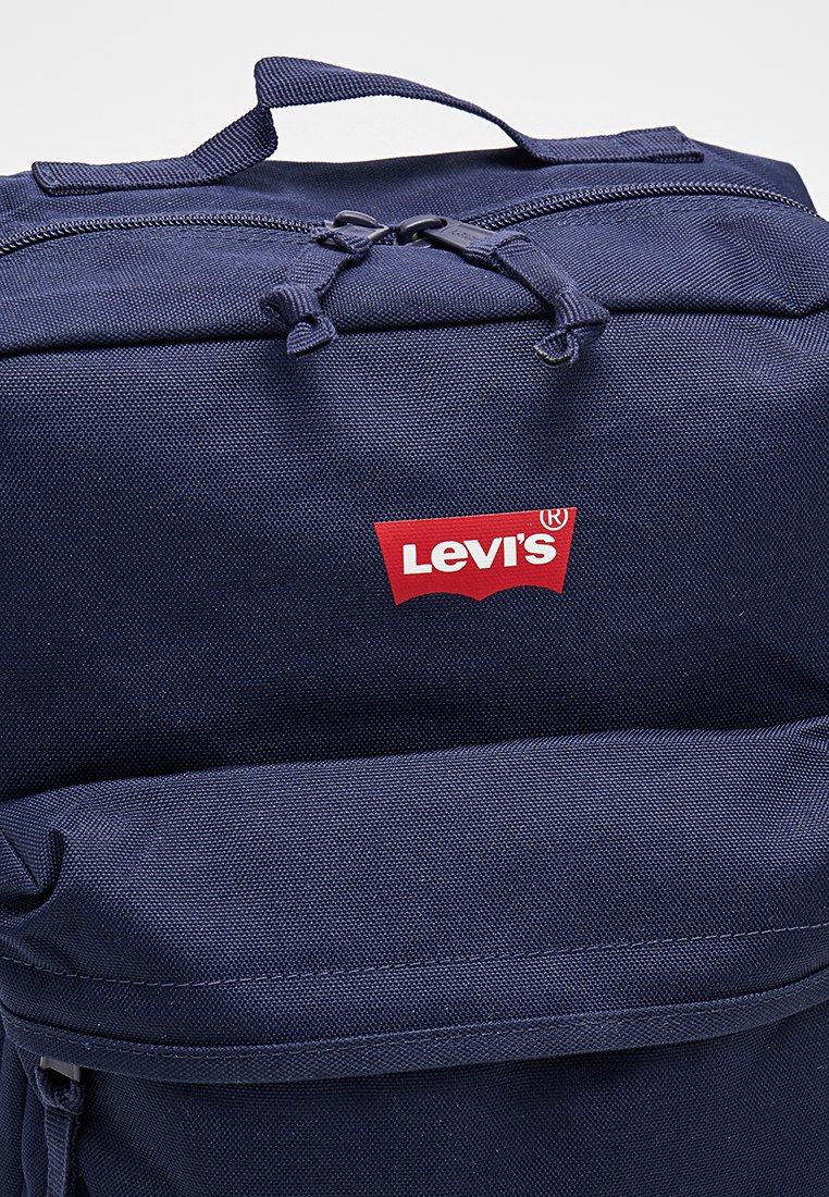 Mochila Levi's azul oscuro con asa superior, doble cremallera y bolsillo delantero visible sobre un fondo liso.