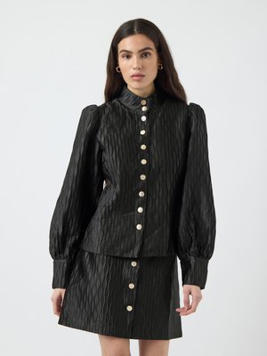 Black textured shirt with puffed sleeves, button front, and a matching skirt. Features a wavy pattern and round gold-tone buttons.