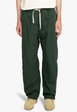 Green drawstring pants made of lightweight fabric, featuring a relaxed fit with subtle stitching details and side pockets.