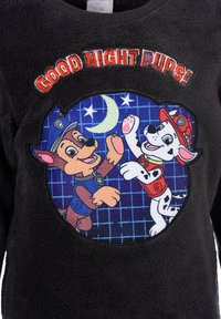 Pullover in pile nero con la scritta "Buona notte cuccioli!". Il design presenta cani animati su uno sfondo a quadri blu, con una luna e stelle.