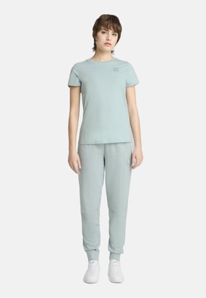 Lichtgroen sportoutfit met een aansluitend T-shirt met korte mouwen en bijpassende joggers met elastische boorden, beide gemaakt van een zachte stof.