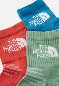 Drei Paar Socken in Rot, Grün und Blau, mit gerippten Bündchen und dem "The North Face"-Logo in Weiß auf jeder. Strukturierte Strickoptik.