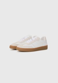 Sneakers bianchi con dettagli in suede, suola in gomma color caramello, design classico con lacci, con due strisce orizzontali sul lato.
