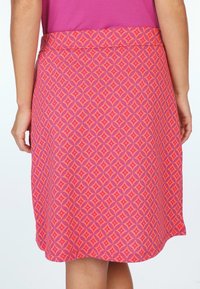 Pink patterned skirt featuring a geometric diamond design in lighter shades, with a smooth texture and a waistband.