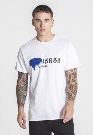 Weißes Baumwoll-T-Shirt mit einem blauen Farbspritzendesign und schwarzem Text "ANAGH MADRID". Kurze Ärmel und ein klassischer Rundhalsauschnitt.