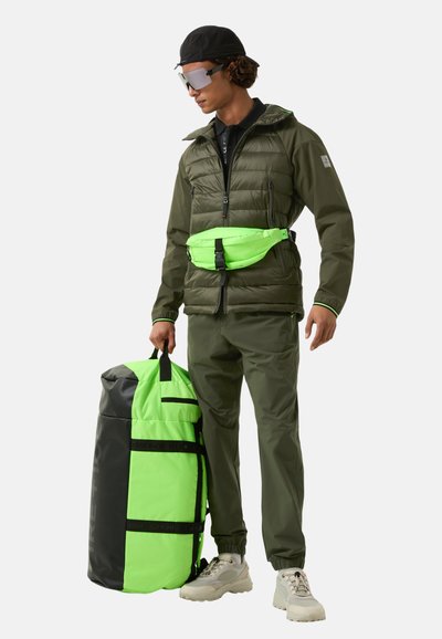 Green puffer jacket, neon green waist bag, matching pants, and a large green and black duffel bag. Features reflective accents and zippers.