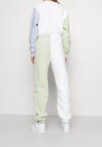 Sweat-shirt léger avec des blocs de couleur en blanc, bleu clair et vert ; assorti à un pantalon de jogging. Tissu doux avec des poignets et une taille élastiques.