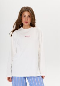 Witte longsleeve sweatshirt met ronde hals en roze "MIRONS" tekst op de voorkant. Zachte stof, ontspannen pasvorm, minimalistisch ontwerp.