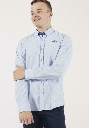 Chemise à manches longues bleu clair avec un motif subtil et des accents bleu foncé au col, arborant un logo brodé.