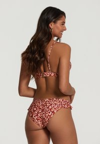 Luipaardprint bikini in tinten van roest en crème, uitgerust met dunne bandjes, een gerafeld randje aan de onderkant en een stevige sluiting op de rug.