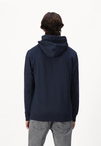 Navyblauwe hoodie gemaakt van zachte stof, met een relaxte pasvorm, lange mouwen en een kangoeroe zak aan de voorkant.