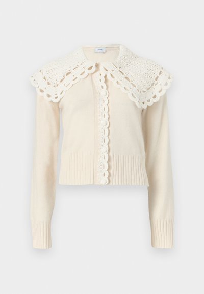 Κρεμ πλεκτή ζακέτα με μακριά μανίκια, με κυματιστά τελειώματα και φαρδιά, κροσέ δαντέλα στο γιακά.