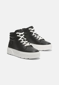 Svarta läder hög-top sneakers med vita snören, med en texturerad yta och en tjock vit plattformssula med räfflade accenter.