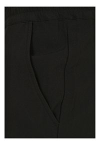 Zwarte stoffen broek met een elastische tailleband, voorzien van zijzakken en vouwlijnen, gemaakt van een soepele katoenstof.