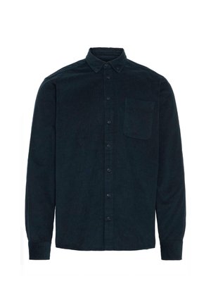 Camicia in velluto a coste verde scuro, con maniche lunghe, pattina frontale, colletto a punta e una tasca singola sul petto. Tessuto testurizzato con righe verticali.
